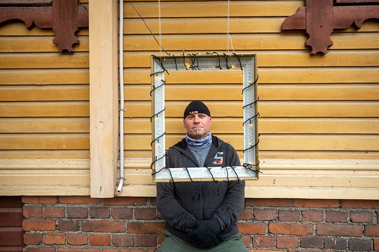 Ihminen katsoo läpi kehysten, jotka roikkuvat talon ulkopuolella.