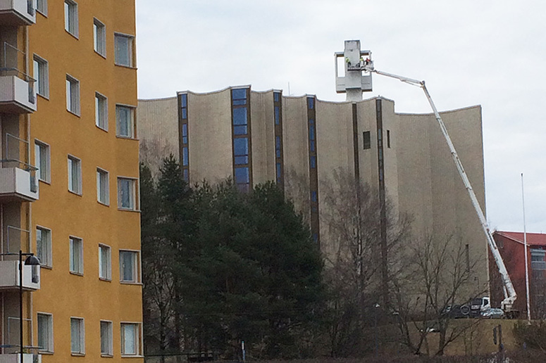 Nostokurki ulottuu kirkon katolla olevalle ristille ja vasemmalla on kerrostalo.