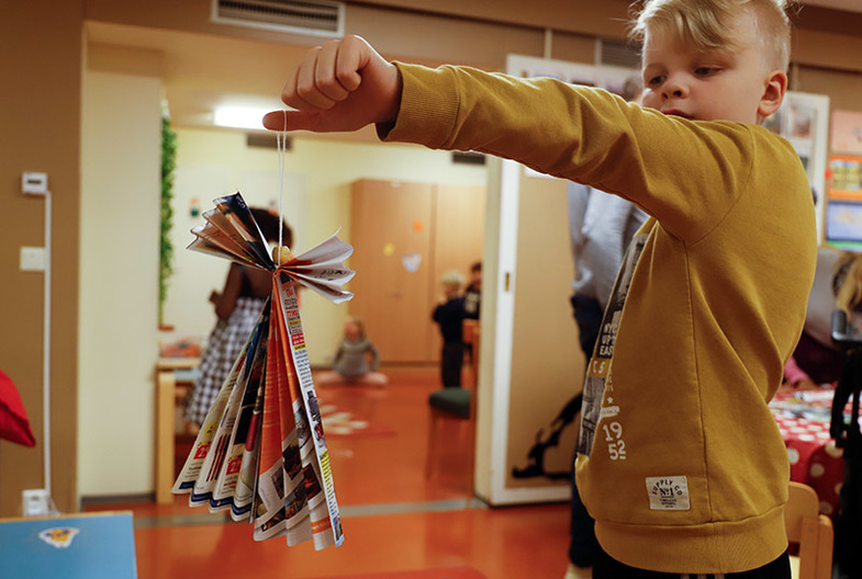 Lapsi esittelee askartelemaansa paperilehti-enkeliä.