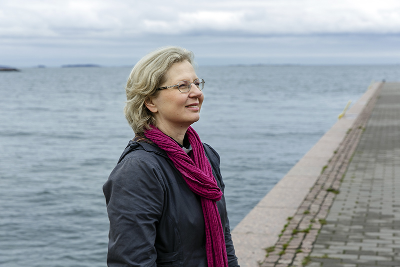 Sivuprofiili-puolivartalokuva naisesta veden äärellä.