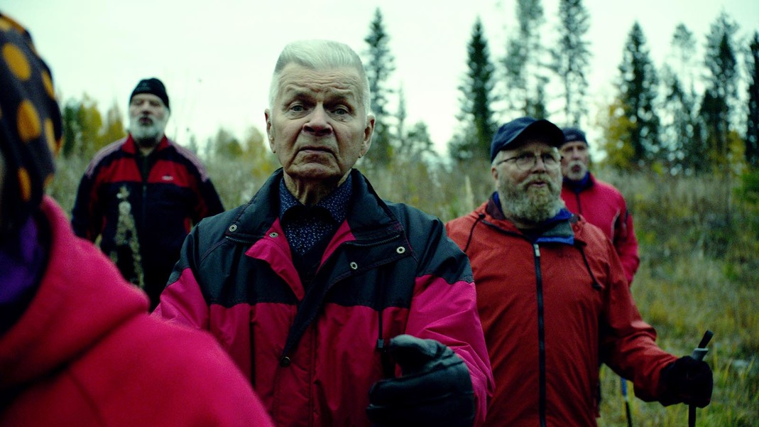 Ihmisiä ulkoilemassa suomaisessa maastossa kävelysauvat käsissä.