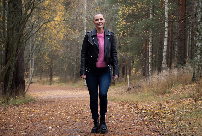 Nahkatakkiin pukeutunut nainen kävelee syksyisellä polulla.