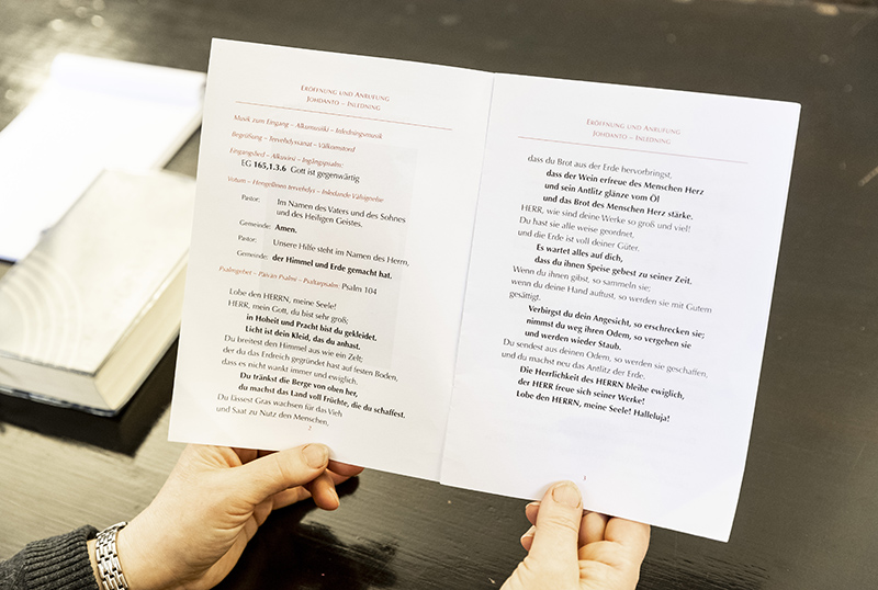 Käsissä on keskeltä taitettu paperi avattuna. Paperilla on tekstiä, josta osa on tummennettu.