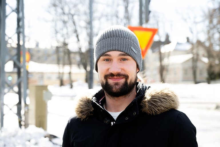 Parrakas nuorimies hymyilee kameraan päin.