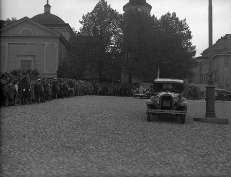 Valtava ihmisjoukka on pakkaantunut Vanhan kirkon eteen ja Keskustorin puoleiselle seinälle katsomaan mukulakivillä ajavaa autoa.