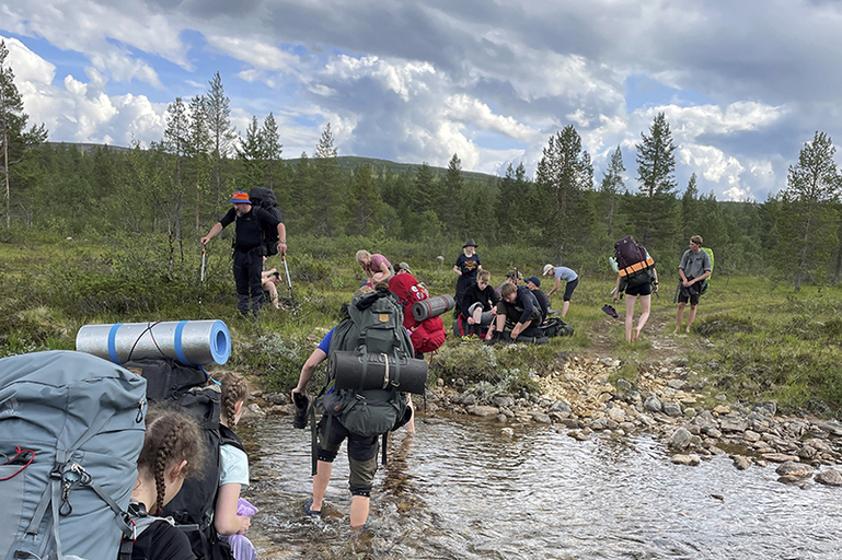 Vaellsurippikoululaiset ylittävät puroa.
