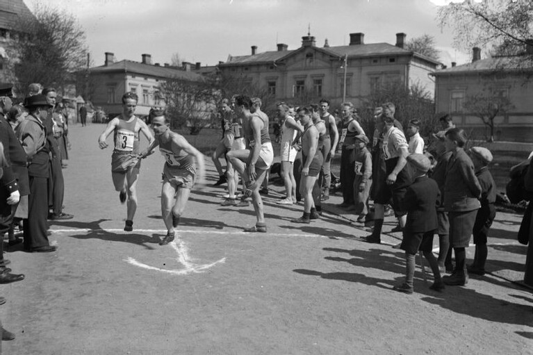 Vanhassa valokuvassa TKT:n joukkue vaihtaa viestikapulaa.