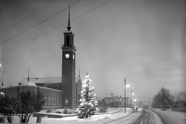 Mustavalkoin valokuva lumisesta kirkosta ja sen ympäristöstä.
