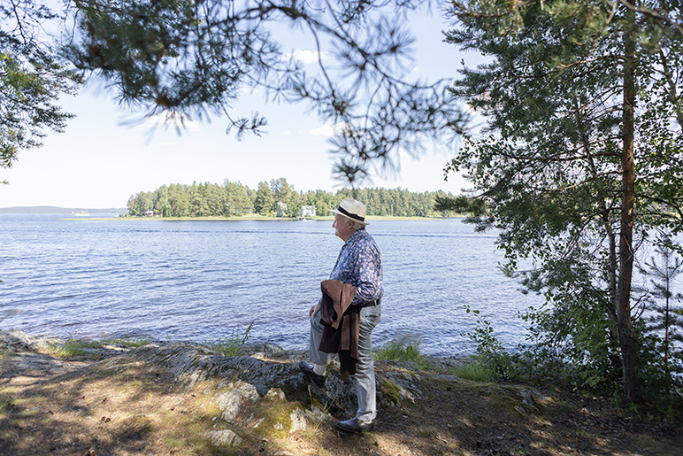 Laaja kuva henkilöstä rannalla katselemassa järvelle päin.