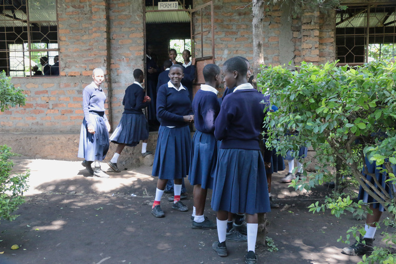 Savitiilisen rakennuksen edessä on joukko tyttöjä koulupuvuissaan. Heistä osa on jo menossa sisään rakennukseen. Ikkuna-aukoissa on metalliset rakenteet, mutta ei laseja.