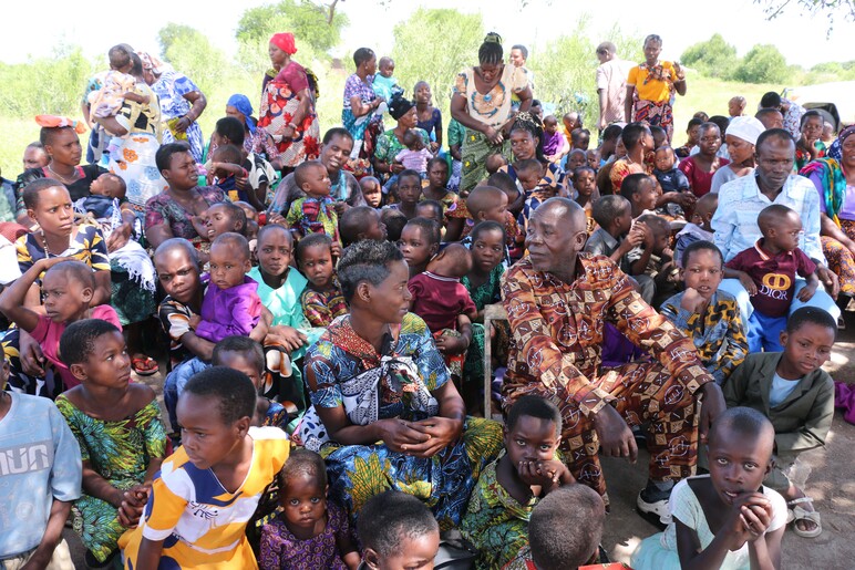 Paljon ihmisiä istuu auringonpaisteessa. Heistä suurin osa on lapsia.
