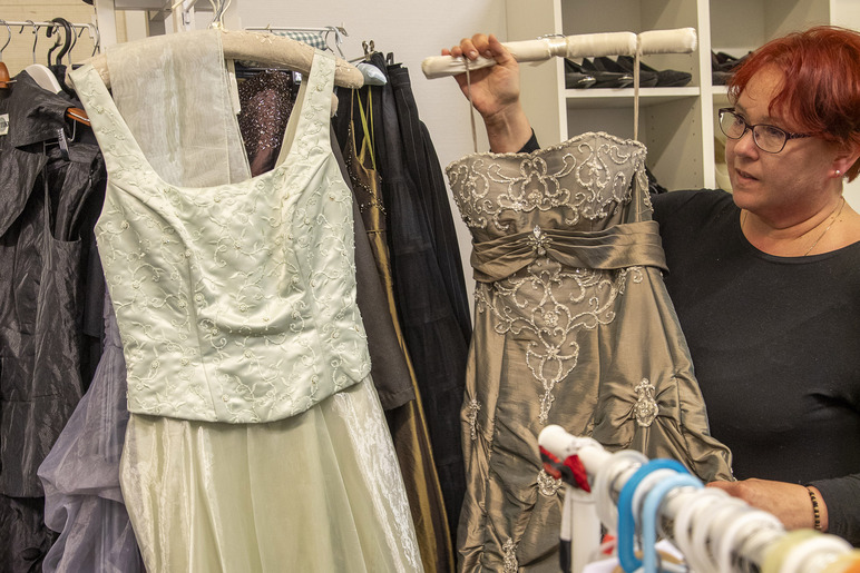 Henkilö nostaa juhlamekkoa rekkiin, jossa on muita mekkoja.