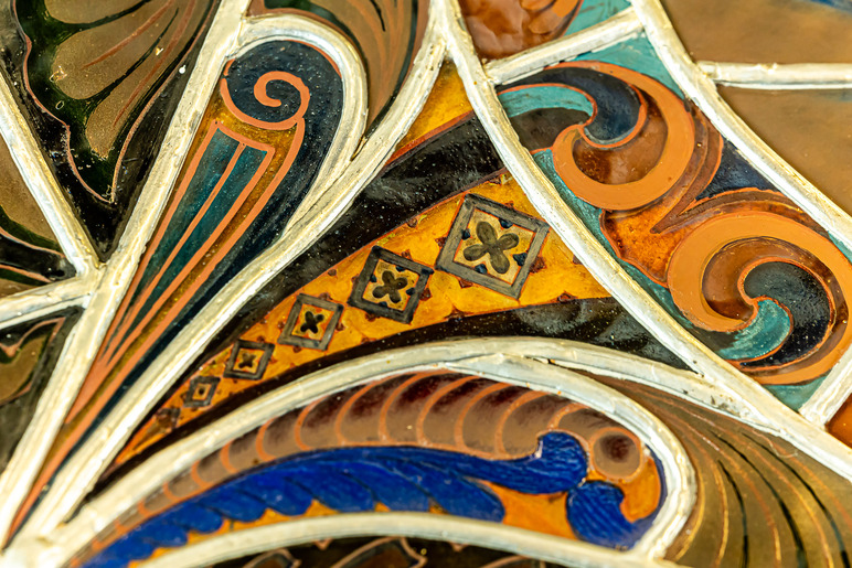 Värikkäitä kuvioita kaarevissa muodoissa, joita kehystävät niin ikään kaartuilevat metalliset reunat.