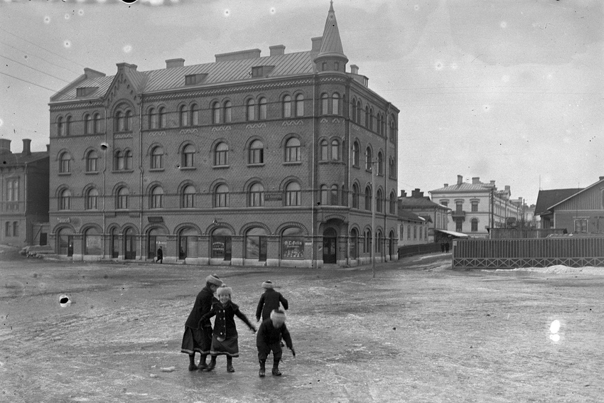 Lapsia jäisellä kadulla. Taustalla iso tiilirakennus.