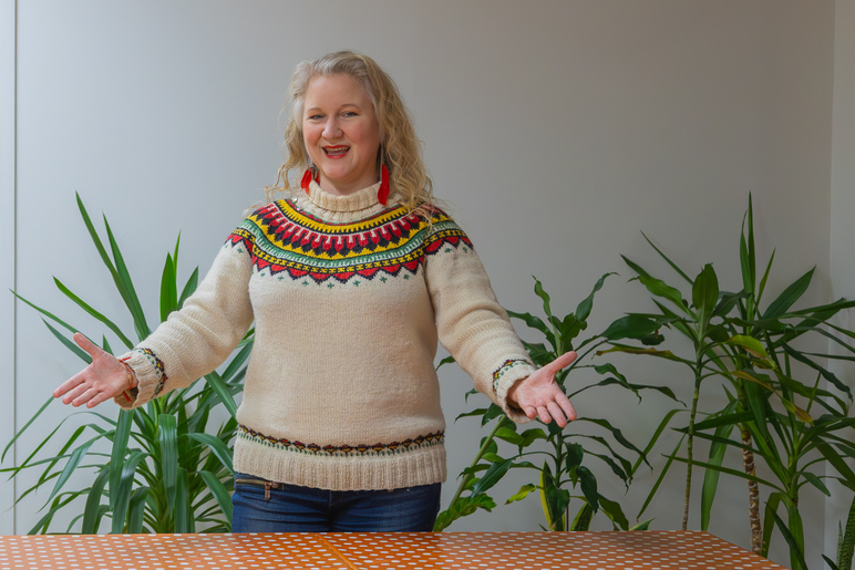 Nainen seisoo kädet avoinna ja hymyilee.