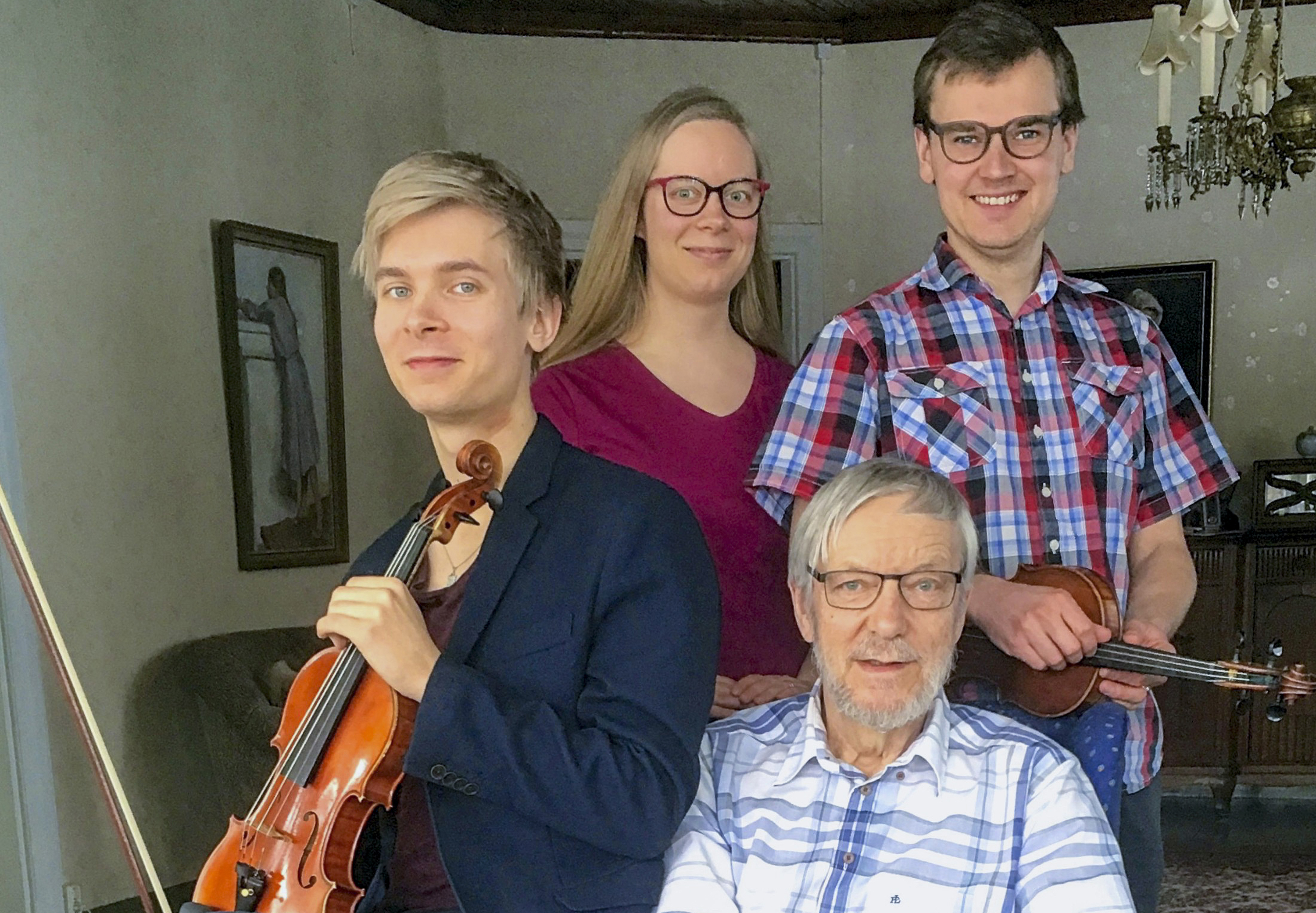 Neljä ihmistä on sisällä huoneessa, heistä kahdella käsissään viulu ja jousi.