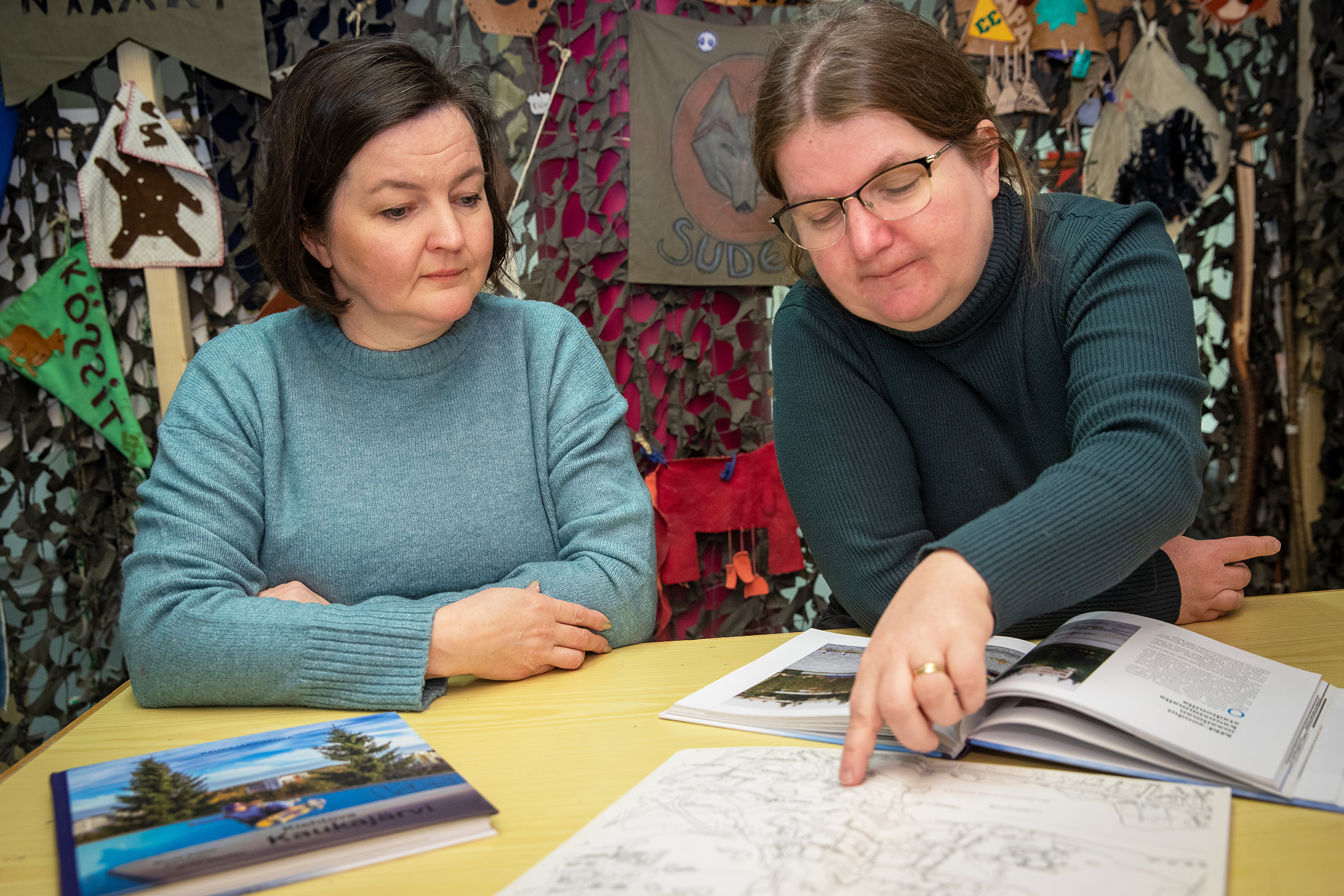 Kaksi naista tutkailee dokumentteja pöydän ääressä.