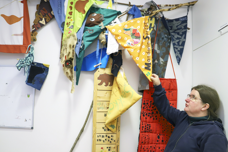 Henkilö kurkottelee kädellään katosta roikkuvia kolmiomuotoisia kankaita.